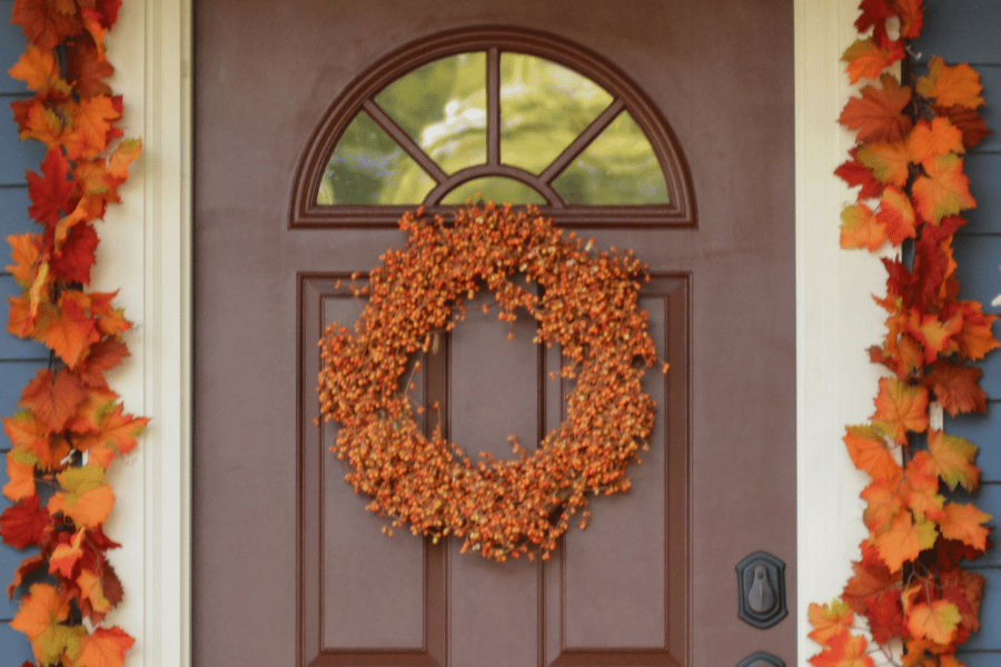 front door with fall wreath and autumn leaves 