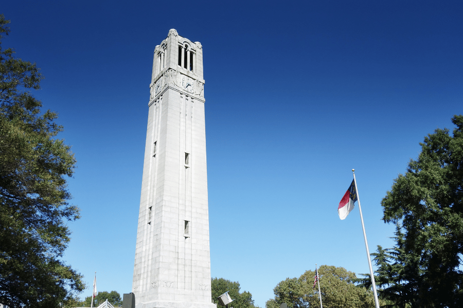 NC State Belltower on campus with NC flag