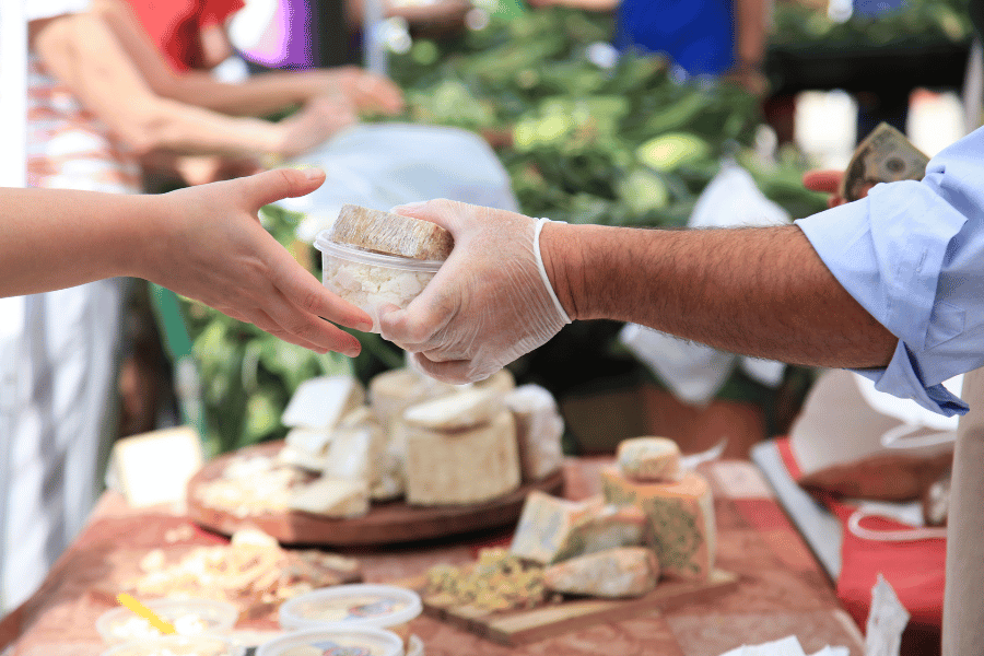 Someone buying fresh cheese at farmers market 