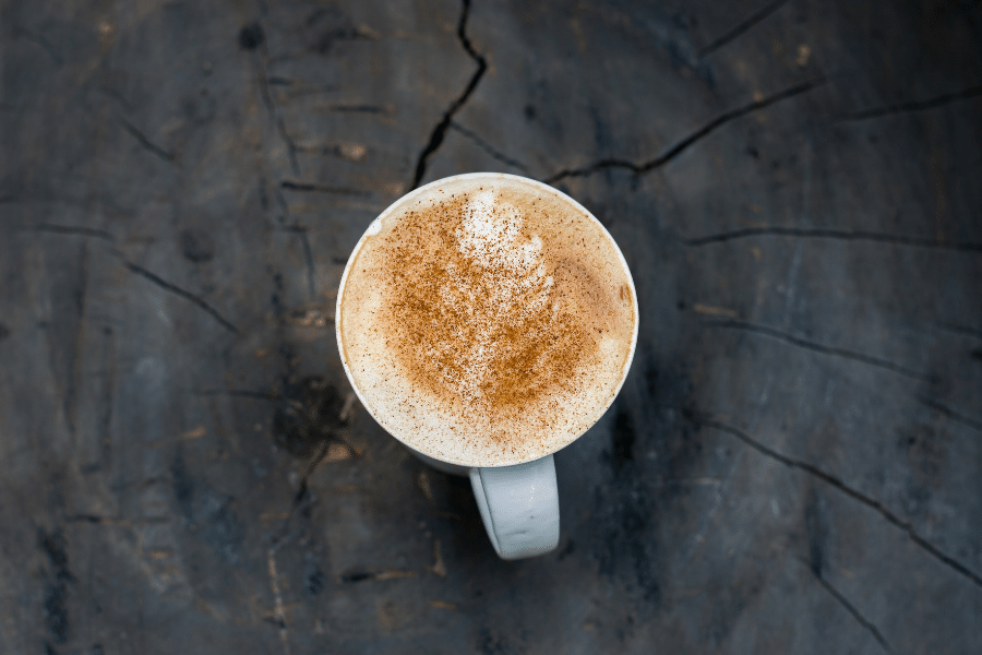 cinnamon latte in a white mug on a wood background 