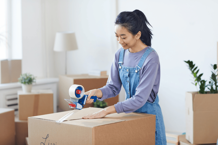 Woman packing up a box and sealing it with packing tape for a move 
