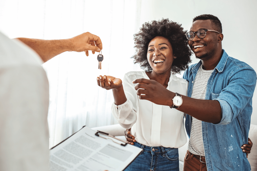 Real estate agent handing new house keys to a couple 