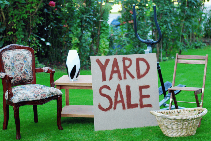 yard sale sign with old furniture for sale in a yard