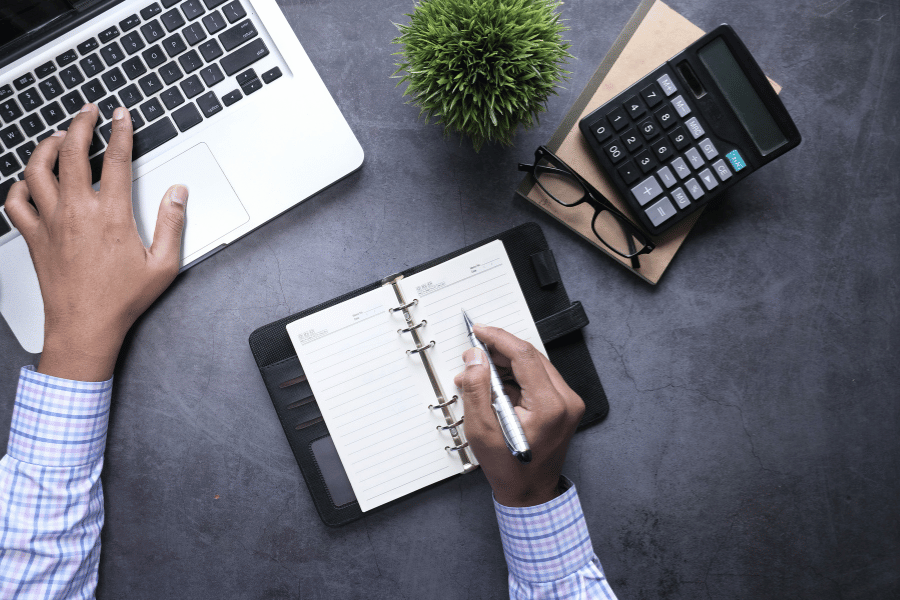 Real estate agent at a desk with laptop, planner, and calculator 