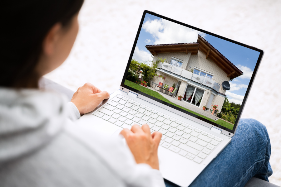 Person with dark hair looking at photo of house on laptop computer