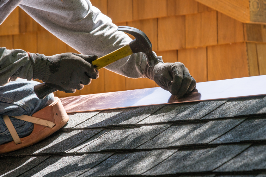 Photo of man with hammer and nail repairing roof shingle