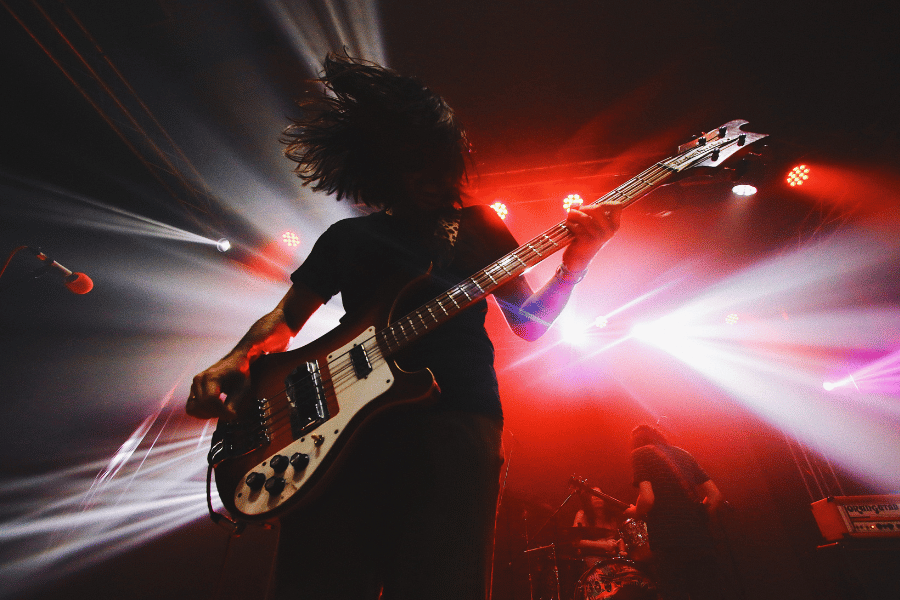 Man playing an electric guitar on stage with red lights